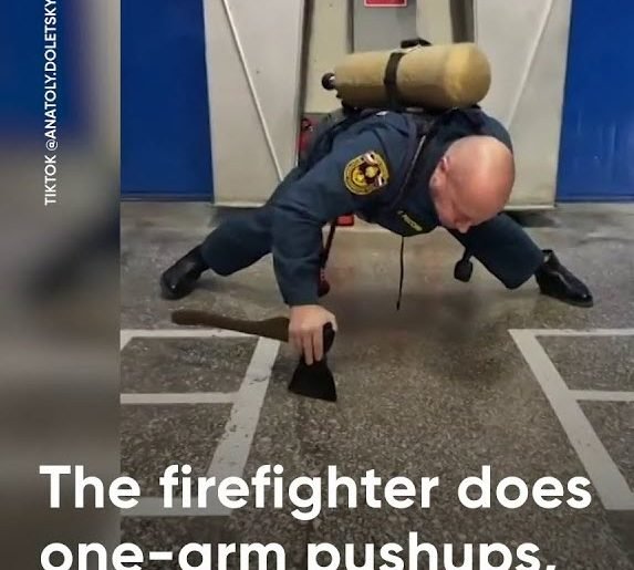 A firefighter does one-arm push-ups.